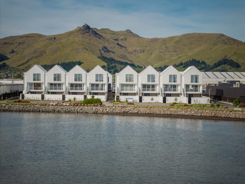 Waterfront row of architecturally designed homes showcasing bespoke new build houses, modern housing developments, and residential construction projects managed by a New Zealand homebuilding company.