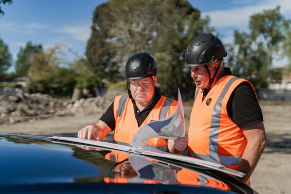 Close up of builders reviewing construction plans on site, highlighting planning accuracy, building expertise, and quality construction management.