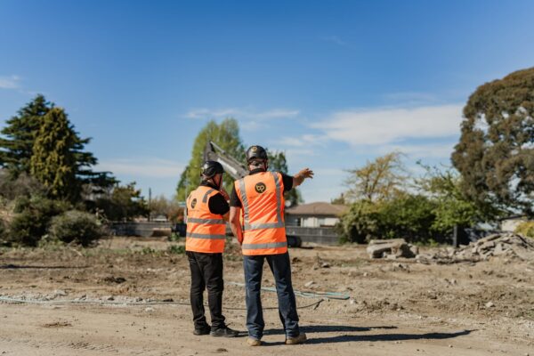 Construction supervisors reviewing site progress in an active work zone, representing project oversight, teamwork, and professional construction services.