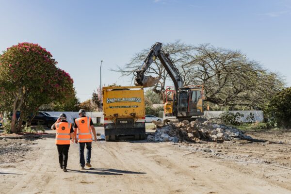 Two construction professionals walking through an active demolition and groundworks area, showcasing the early stages of building construction, project construction planning and the structured approach used in home construction and Commercial Construction projects.