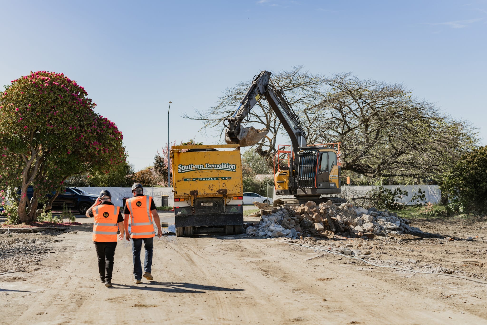 Two construction professionals walking through an active demolition and groundworks area, showcasing the early stages of building construction, project construction planning and the structured approach used in home construction and Commercial Construction projects.