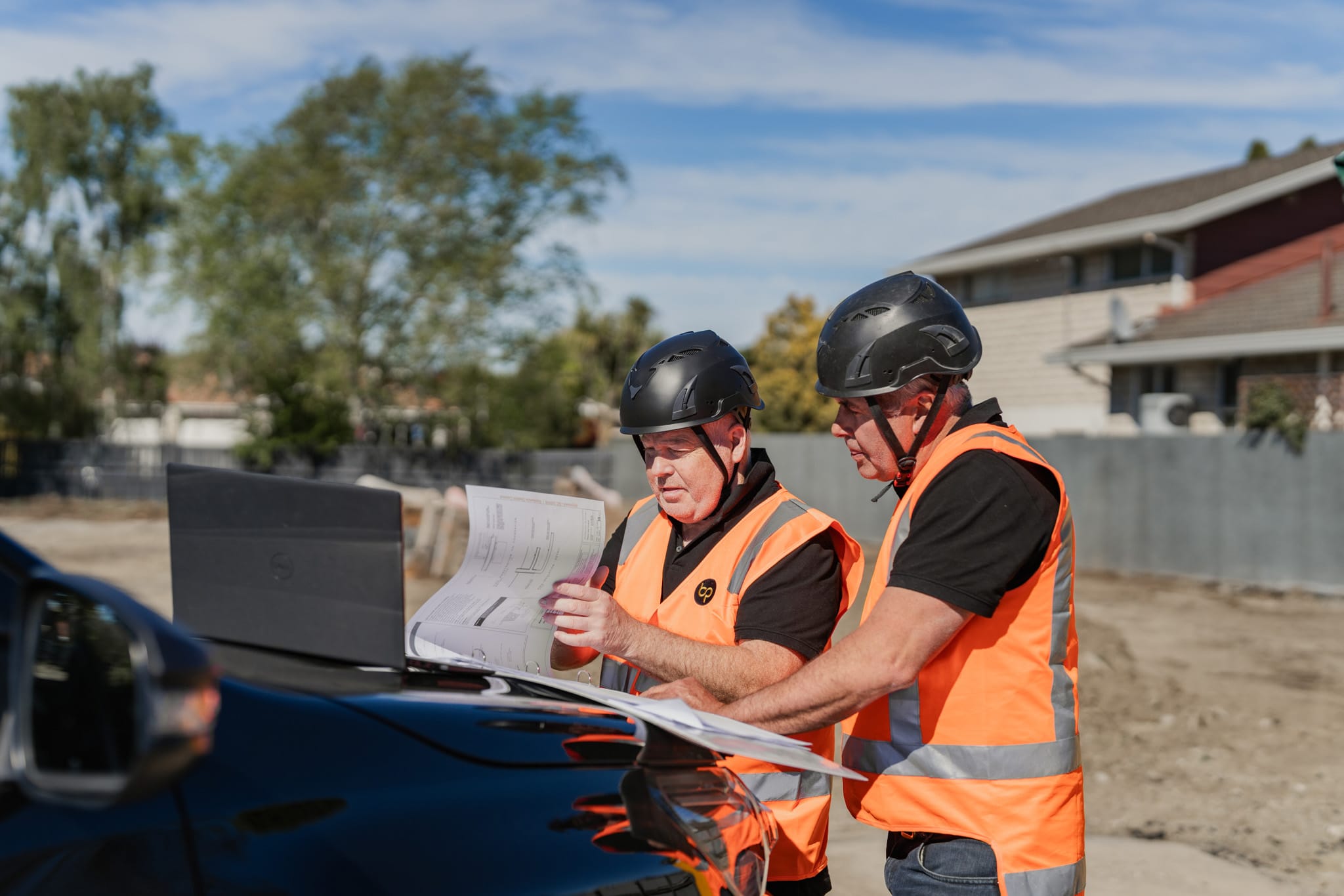 Project managers reviewing architectural plans on site during new housing developments, highlighting construction NZ experience, manage construction projects capability, building reports, new build developments and architectural build processes.