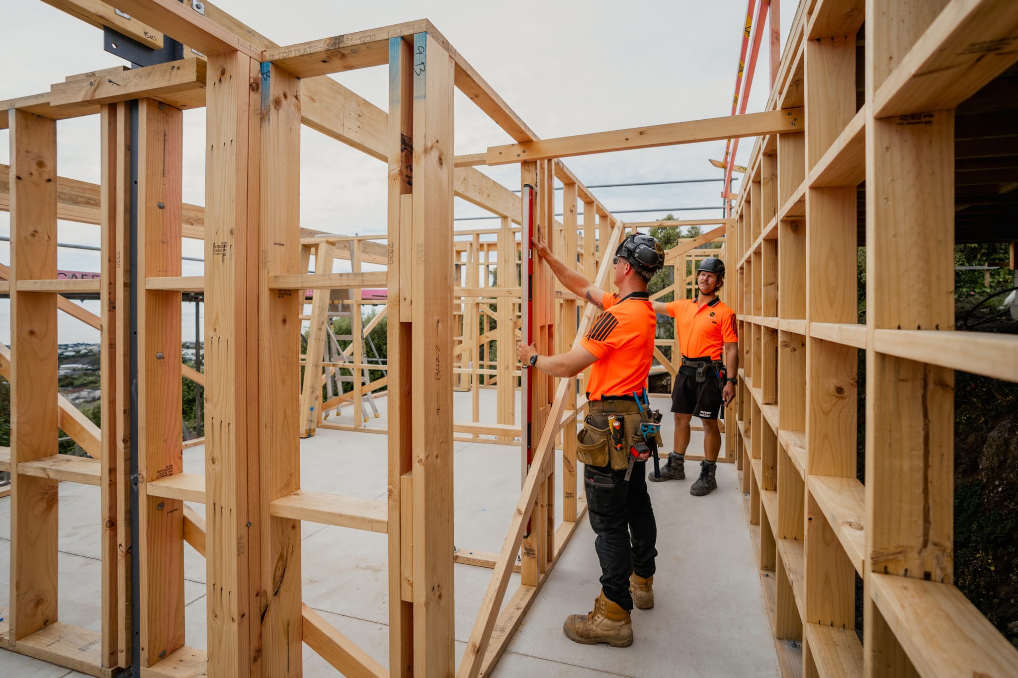 Builders framing timber walls during new build construction on a hillside site, illustrating construction management, architectural plans in action, building construction processes and a homebuilding company skilled in managing construction projects and new home developments.