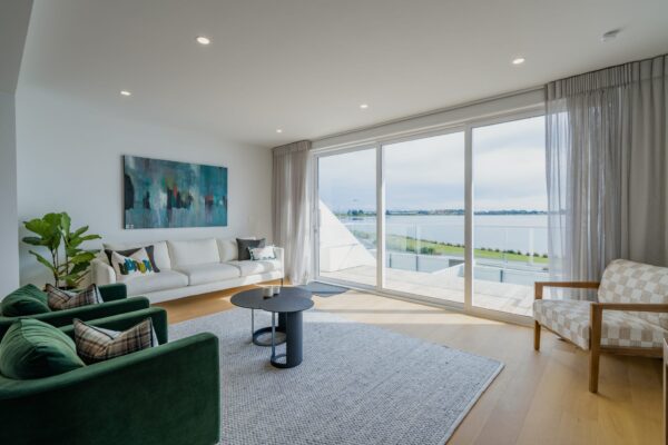 Modern living room with large sliding doors and water views, showcasing interior design and build quality within an architecturally designed townhouse.