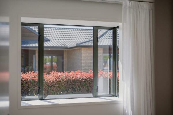 A view through modern aluminium windows in an architecturally designed home, demonstrating the precision of building construction, bespoke renovations and the quality expected from home builder companies producing new builds and completing detailed property inspection report requirements.