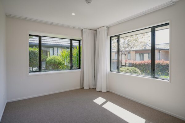 A bright bedroom in a modern house with large windows overlooking landscaped gardens, illustrating new build homes within new home developments constructed by a homebuilding company skilled in managing construction projects, architectural builds and providing building inspection report compliance.