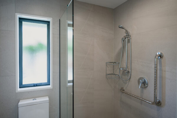 An upgraded bathroom featuring an accessible shower with handrails, part of a bespoke refurbishment aligned with building construction guidelines, architectural plans and building reports, suitable for aged care construction, home repair insurance work and professional home builder renovations.