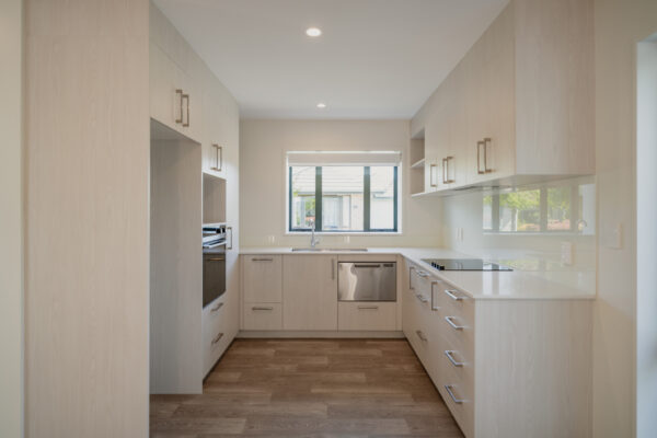 A light, modern house kitchen showcasing a bespoke refurbishment with new cabinetry, updated appliances and clean architectural lines, representing high-quality home construction, renovations and construction management by a homebuilding company experienced in new builds, Design and build projects and aged care refurbishment.