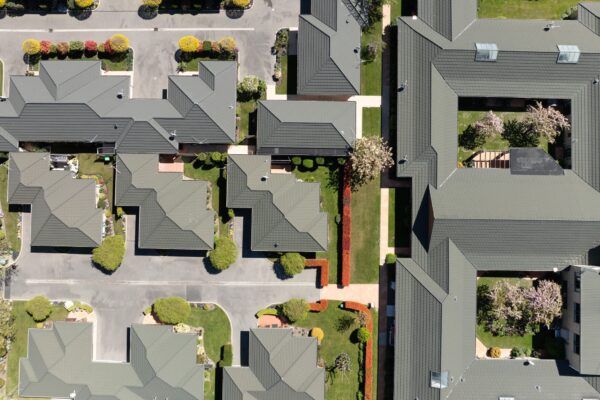 A drone view of new housing developments arranged in a landscaped village layout, showcasing construction projects, architectural homes and new build developments created by construction NZ professionals handling everything from architectural plans to building inspection report delivery.