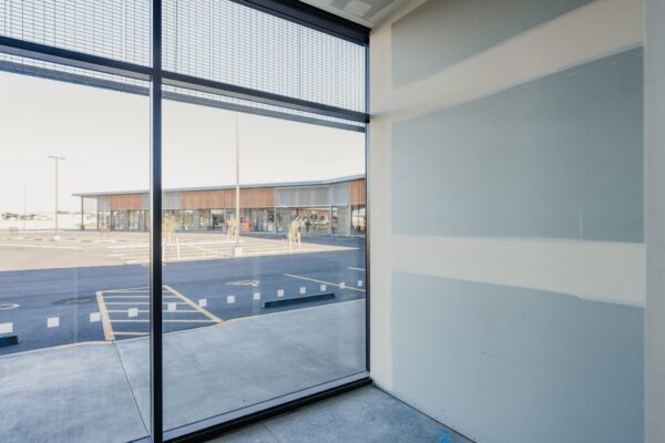 A commercial space under construction viewed through a large window, showing early-stage commercial fit out work, Commercial Construction progress, construction NZ quality, and a homebuilding company skilled in project construction and refurbishment.