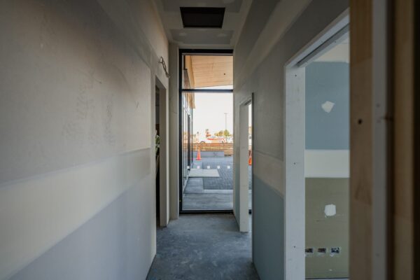 A corridor in a commercial refurbishment project with framing and plasterboard in progress, highlighting Commercial Construction, construction management, bespoke refurbishment, building construction and preparation for a property inspection report.